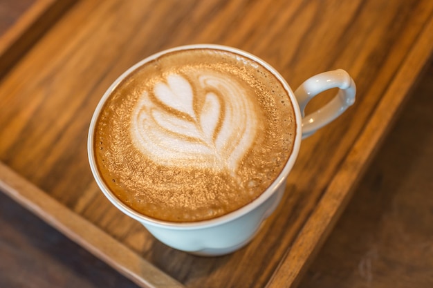 Photo a cup of coffee with heart shape on wooden table