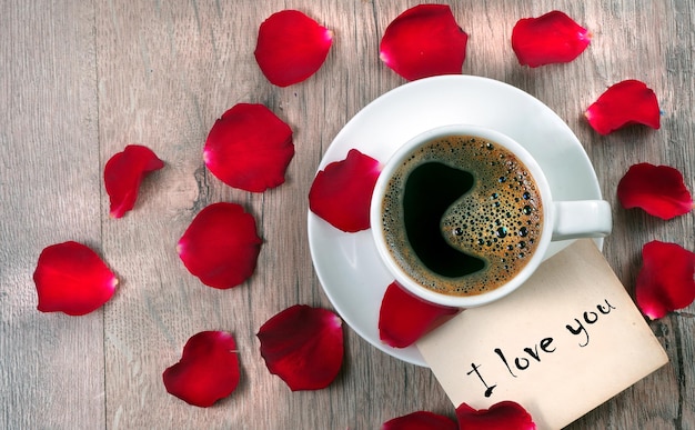a cup of coffee with a heart shaped rose and a card with a cup of coffee with a card that says i love you.