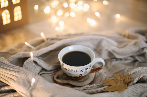 cup of coffee with a knitted beige plaid on background autumn and winter cozy leisure concept