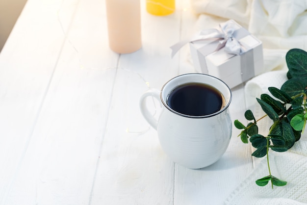 Cup of coffee with knitted scarf on staying on wooden tray in bed, copy space. good morning breakfast