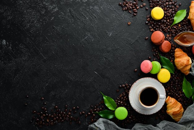 A cup of coffee with a macaroons cake On a black stone background Top view Free space for your text