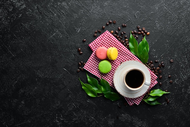 A cup of coffee with a macaroons cake On a black stone background Top view Free space for your text