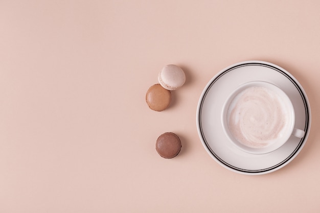 Cup of coffee with macaroons on pastel background