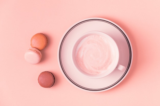 Cup of coffee with macaroons on pastel.