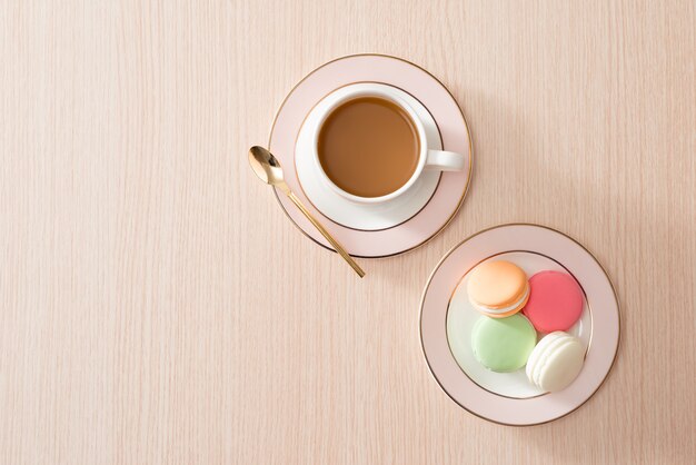 Cup of coffee with macaroons on wooden surface