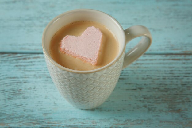 Cup of coffee with marshmallow on wooden table