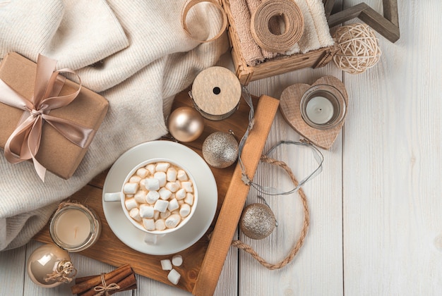 Una tazza di caffè con marshmallow, decorazioni natalizie e un regalo su uno sfondo chiaro. il concetto di natale e capodanno. vista dall'alto, copia dello spazio.