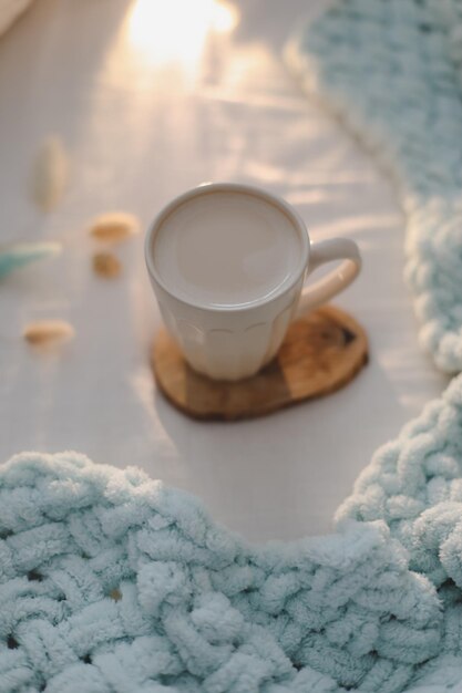白いリネンと毛布とベッドの上のミルクとコーヒーのカップベッドのコンセプトでモーニングコーヒー