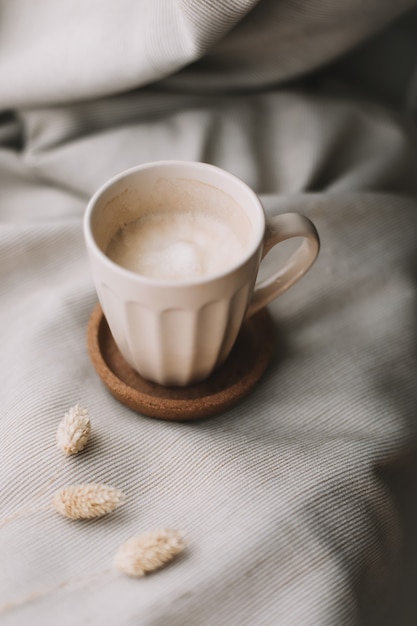 Cup of coffee with milk on beige plaid