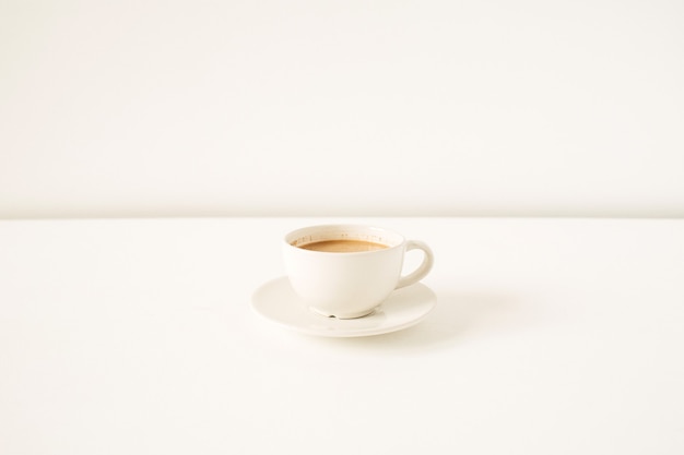 Cup of coffee with milk on white table