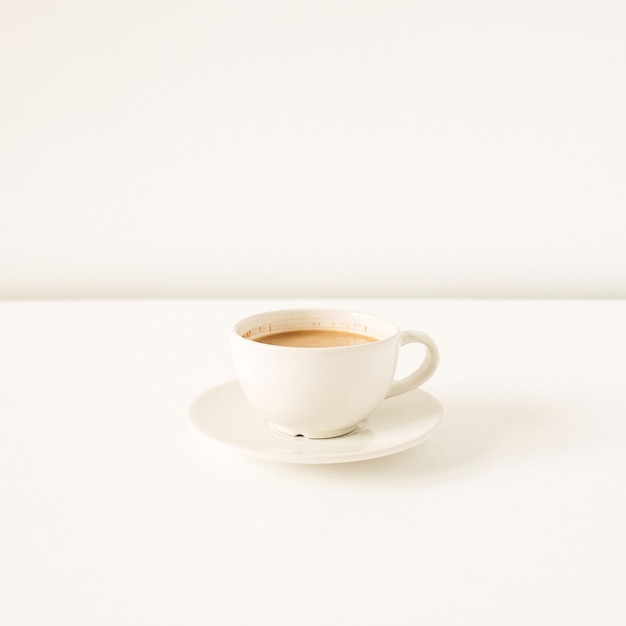 Cup of coffee with milk on white table