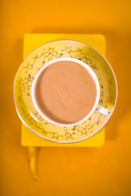 Cup of coffee with milk on the yellow background