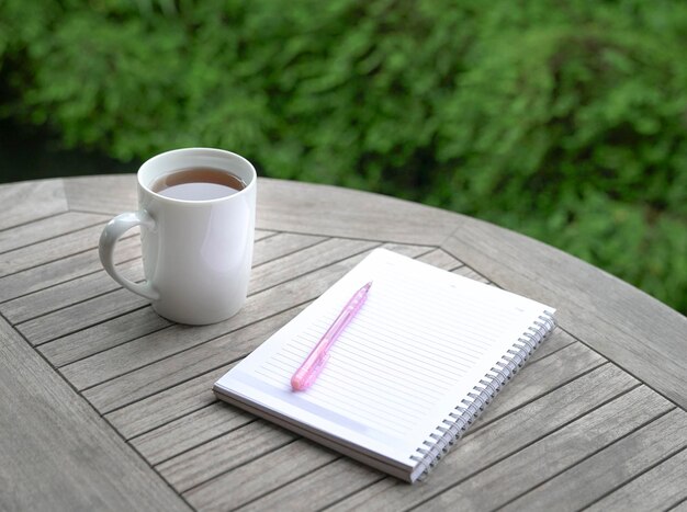 Cup of coffee with notebook and pen on top of table