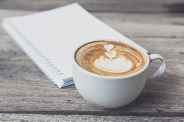 cup of coffee with notebook on wood table