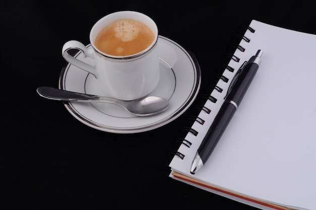 A cup of coffee with a notepad.