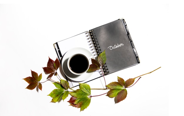 Photo cup of coffee with open notepad and chestnut leaves isolated on white background