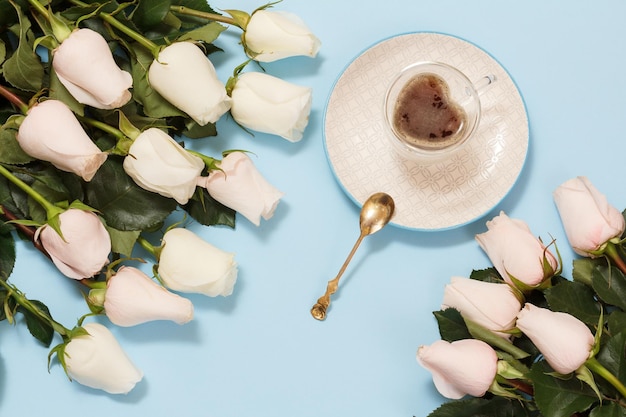 Cup of coffee with rose flowers on the blue background