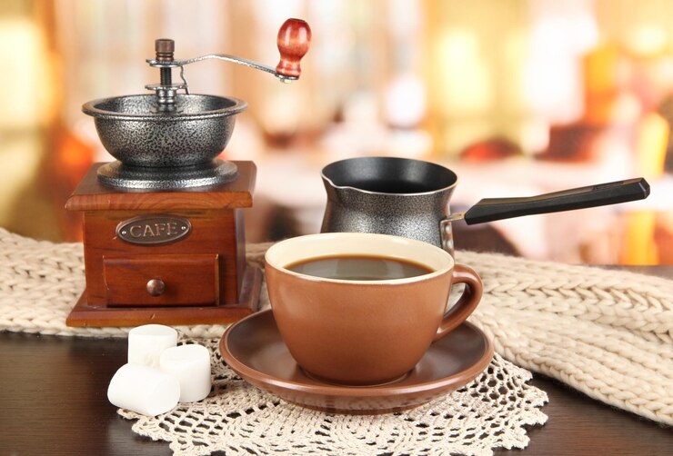 Photo cup of coffee with scarf and coffee mill on table in room