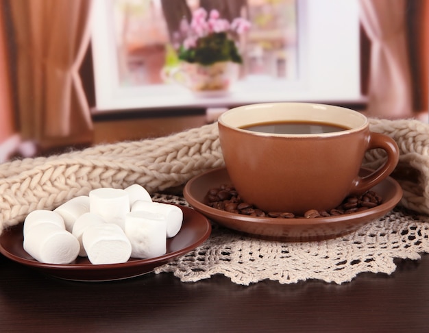 Cup of coffee with scarf on table in room