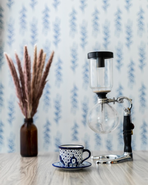 Cup of coffee with a siphon coffee maker, a branch of fluffy pampas grass in a little  bottle