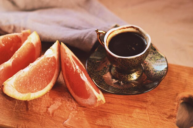 A cup of coffee with a slice of grapefruit on a plate