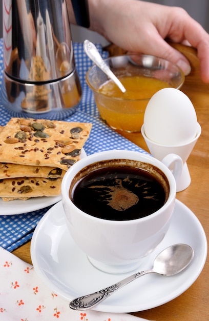 A cup of coffee with a soft-boiled egg and toast for breakfast