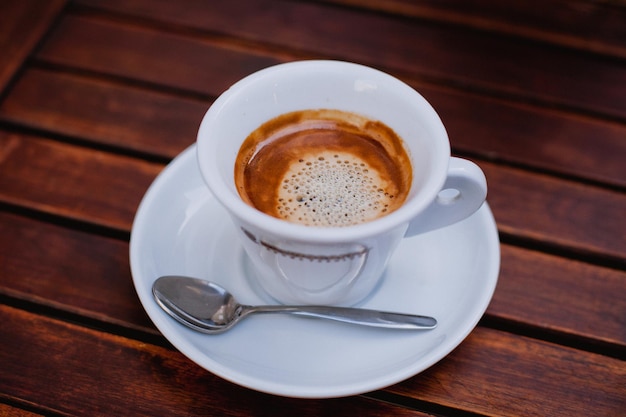 A cup of coffee with a spoon on a wooden table.