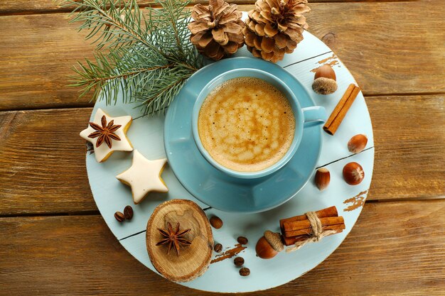 Cup of coffee with star shaped biscuits and Christmas tree branch on wooden mat