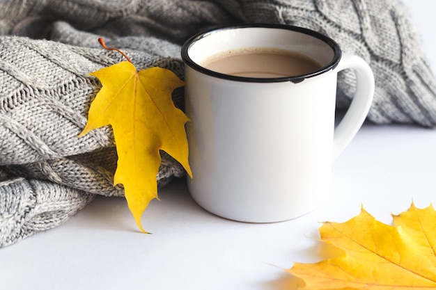 Cup of coffee with sweater and autumn leaves