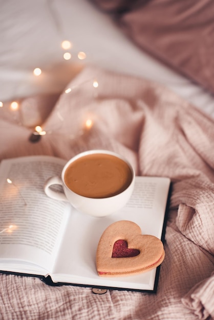 Cup of coffee with tasty cookie on open book close up. Good morning. Breakfast.