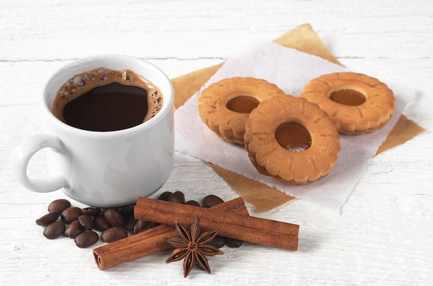 Cup of coffee with tasty cookies on white wooden table