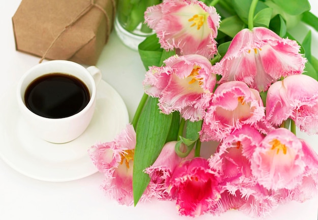 A cup of coffee with tulips a gift for mom or a breakfast with\
flowers