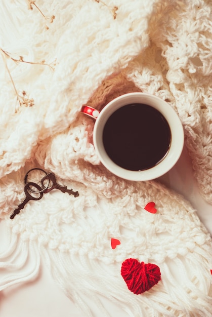 Cup of coffee with warm knitted scarf