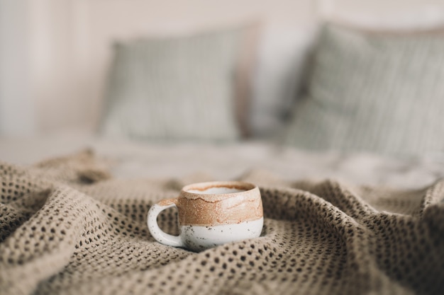 Cup of coffee with warm plaid in bed