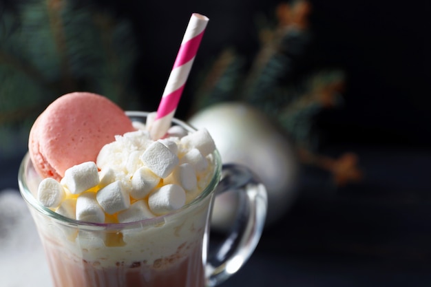 Photo cup of coffee with whipped cream and macaroon on black background