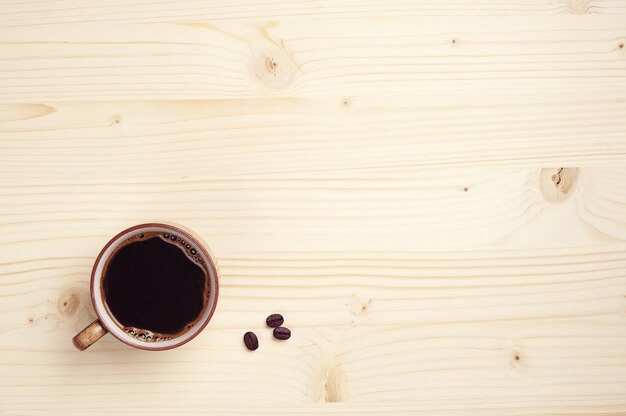 Cup of coffee on wooden background. With place for text.