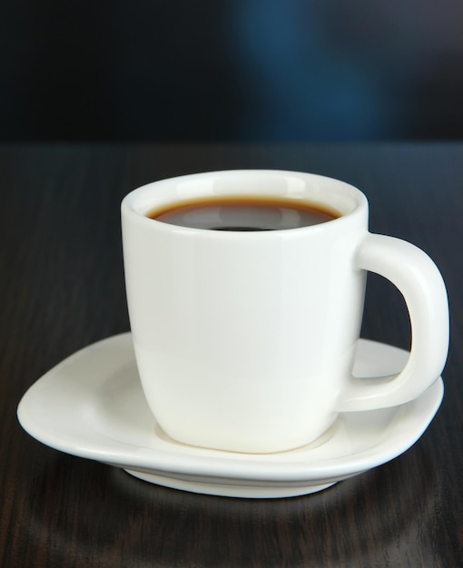 Cup of coffee on wooden table on bright background