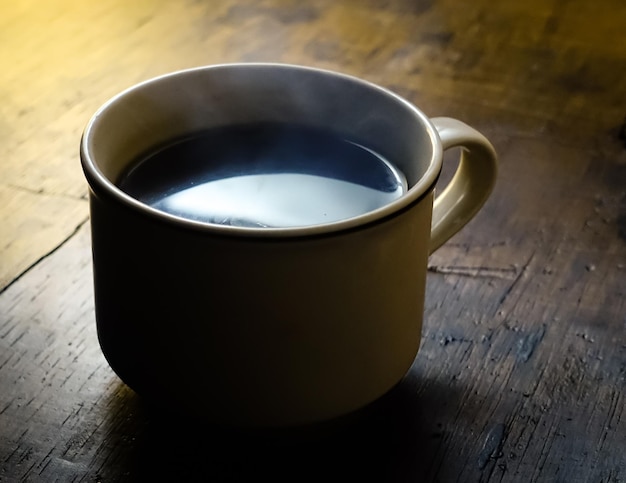 a cup of coffee on wooden table isolated in dark background international coffee day concept