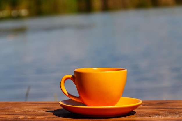 Cup of coffee on the wooden table near the river