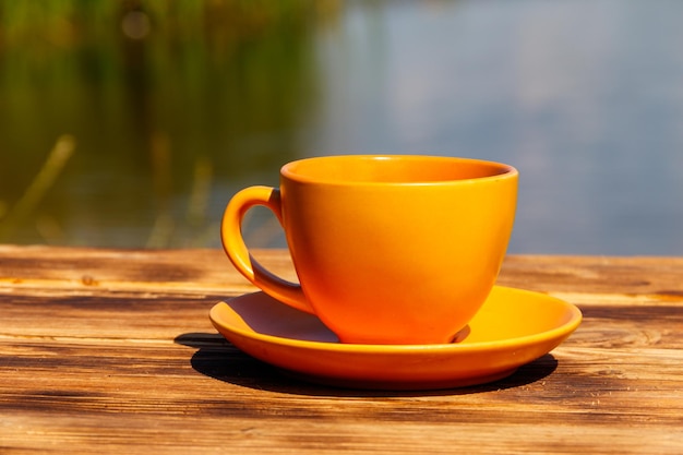 Cup of coffee on the wooden table near the river