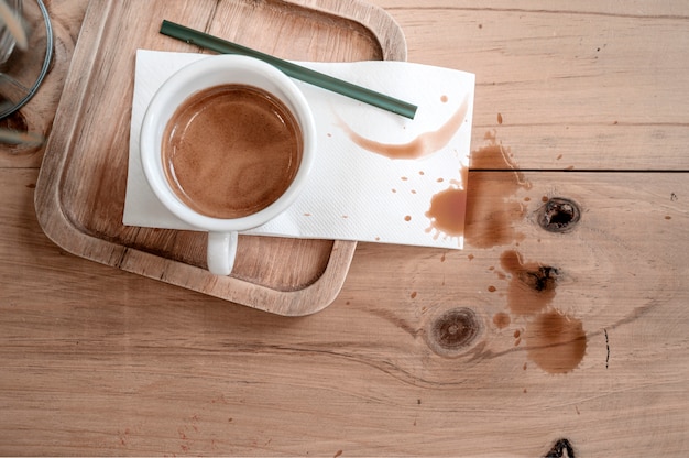 Cup of coffee on wooden table with coffee stains.