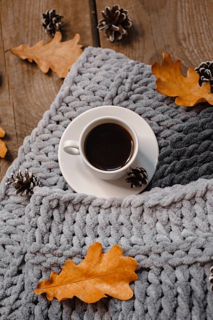 Una tazza di caffè su un tavolo di legno con biscotti, foglie e coni