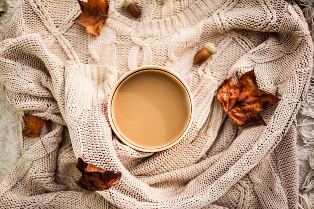 cup of coffee wrapped in a woolen beige sweater