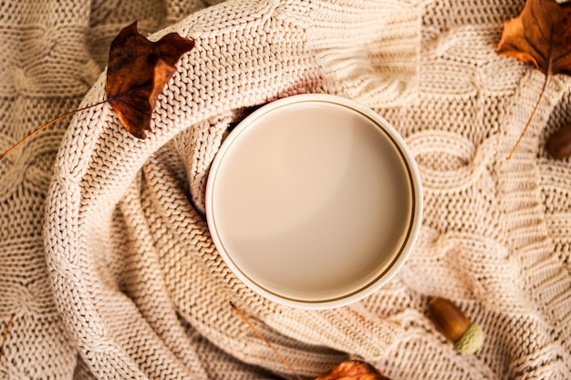 Tazza di caffè avvolta in un maglione di lana beige