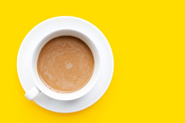 Cup of coffee on yellow background top view