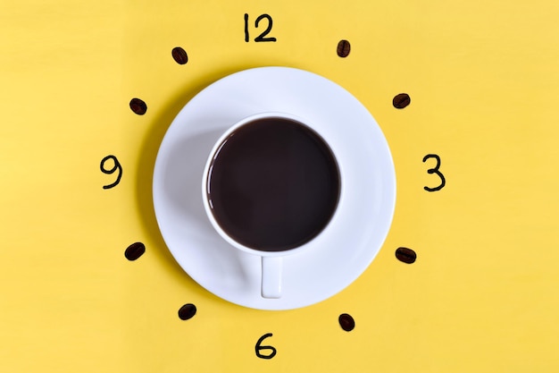 Cup of coffee on a yellow background with watch face at 6 am or 6 pm. Time to drink coffee