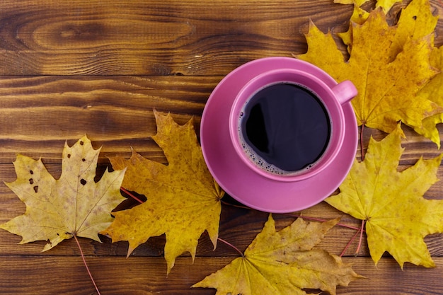 一杯のコーヒーと木製のテーブルに黄色のカエデの葉上面図