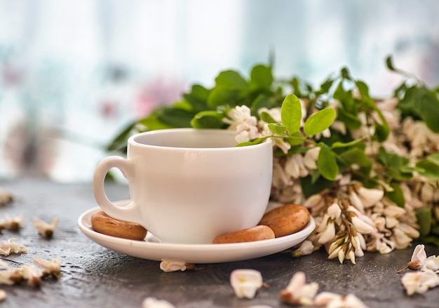 Tazza di caffè e primo piano dell'acacia. una tazza di caffè e fiori di acacia.