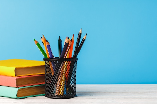 Cup of color pencils and stack of books