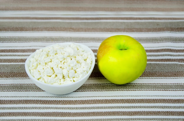 カッテージ チーズのカップと縞模様の綿のテーブル クロスに新鮮なリンゴ 健康的なダイエット食品の朝食